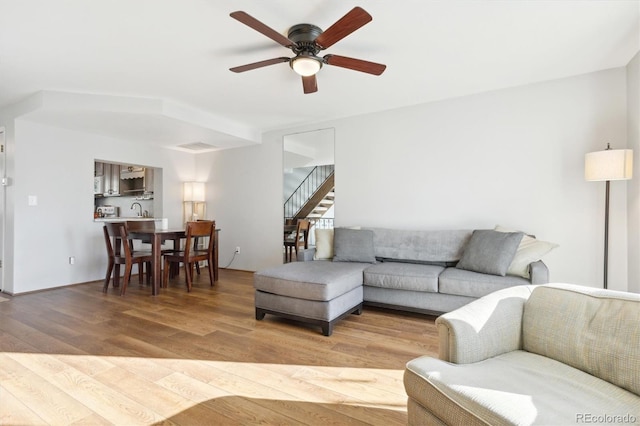 living room featuring ceiling fan, wood-type flooring, and sink