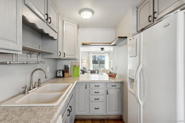 kitchen with sink, white fridge with ice dispenser, white cabinets, and ceiling fan