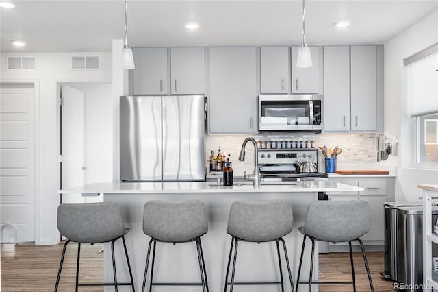 kitchen with visible vents, appliances with stainless steel finishes, and a kitchen breakfast bar