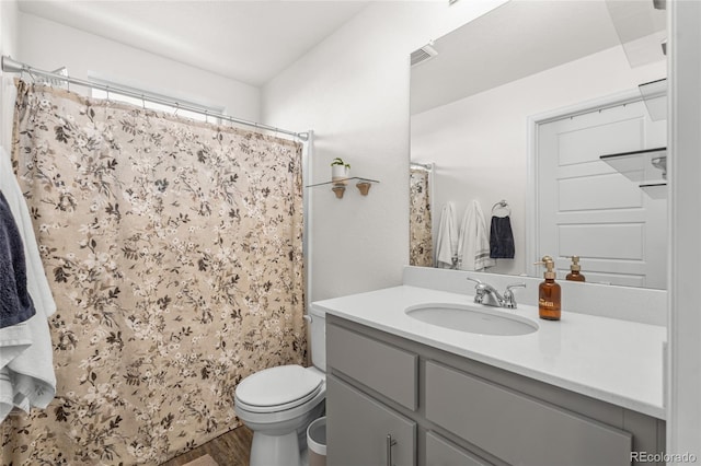 bathroom with visible vents, toilet, vanity, wood finished floors, and a shower with curtain