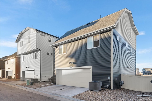 back of house with a garage, concrete driveway, central AC, and fence