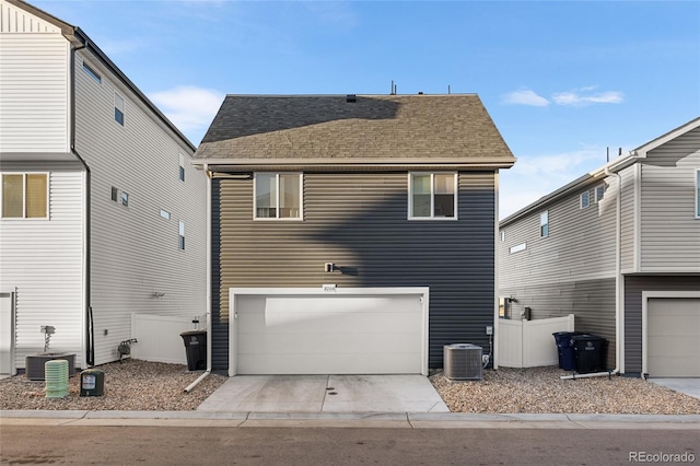 rear view of property featuring a shingled roof, central AC, driveway, and fence