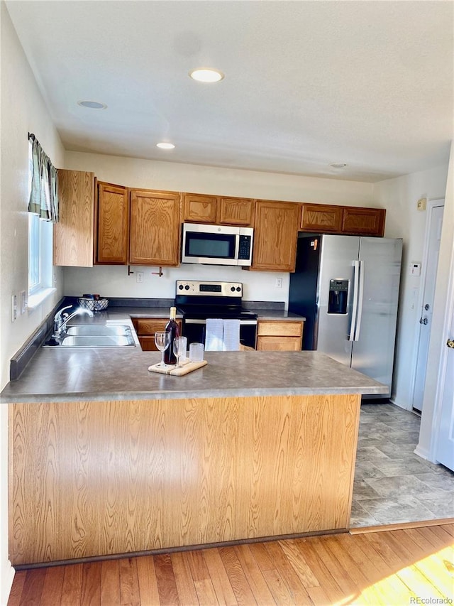 kitchen with stainless steel appliances, sink, and light hardwood / wood-style floors