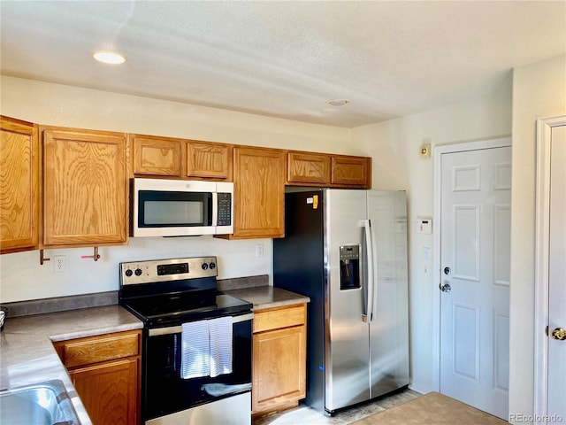 kitchen with stainless steel appliances, brown cabinets, and a sink