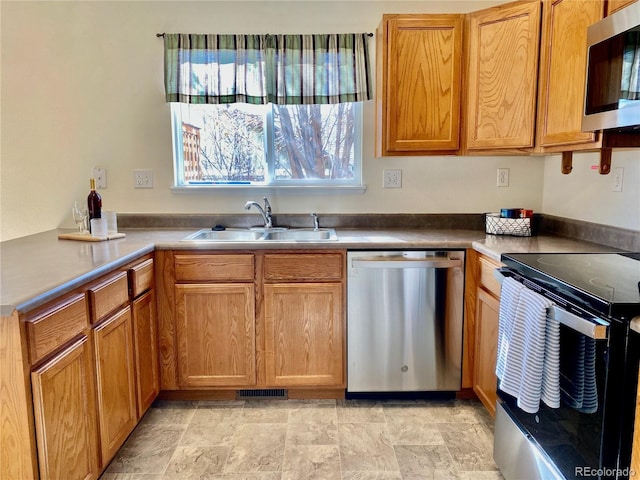 kitchen featuring visible vents, appliances with stainless steel finishes, a peninsula, light countertops, and a sink