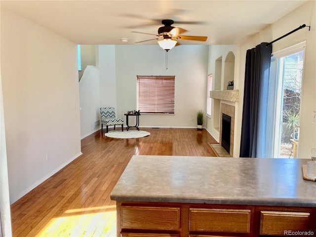 living room with a tiled fireplace, light hardwood / wood-style floors, and ceiling fan