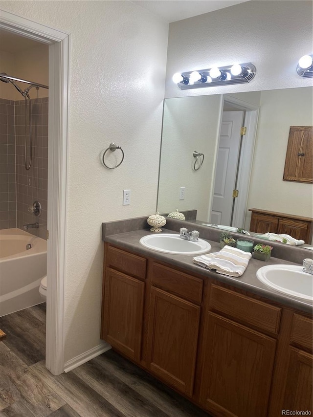 full bathroom featuring tiled shower / bath, vanity, toilet, and hardwood / wood-style floors