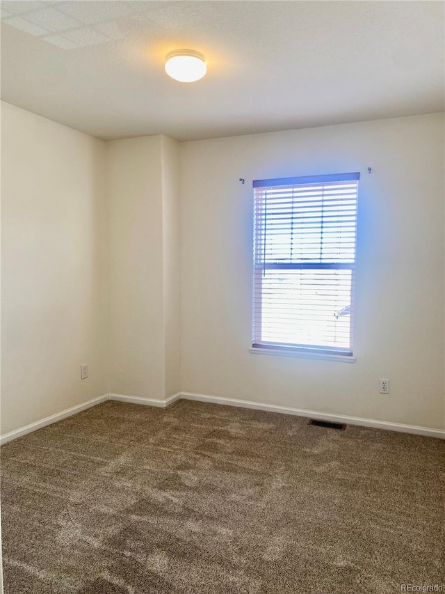 carpeted spare room with visible vents and baseboards