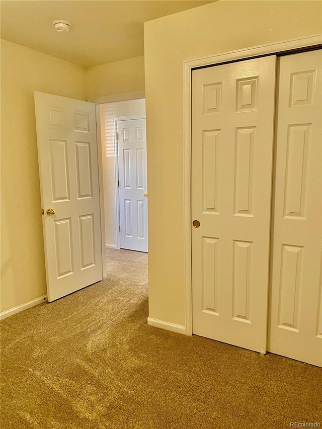 unfurnished bedroom featuring a closet, baseboards, and carpet flooring