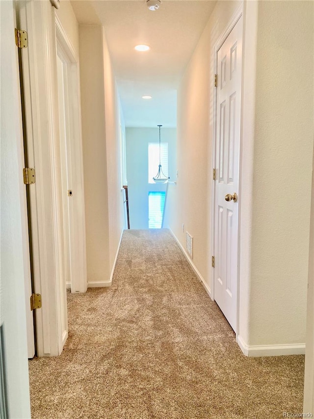 hall with carpet floors, baseboards, and visible vents