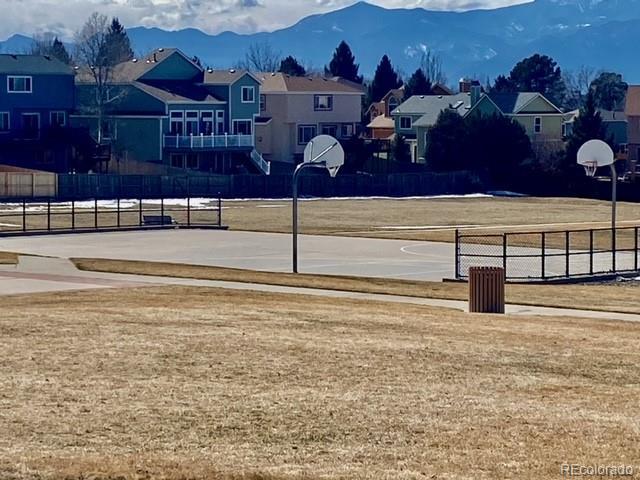 view of basketball court with community basketball court, a residential view, a mountain view, and fence