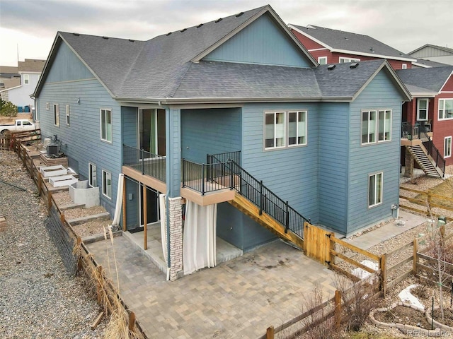 back of property featuring a shingled roof, central air condition unit, a patio, and stairs