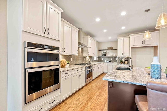 kitchen with double oven, a sink, wall chimney exhaust hood, open shelves, and tasteful backsplash