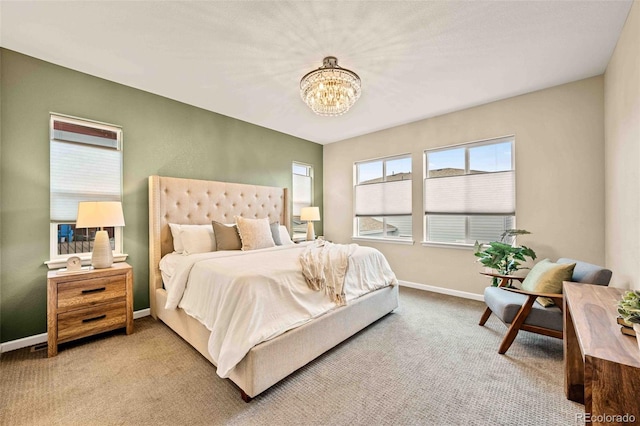 carpeted bedroom with baseboards and a chandelier