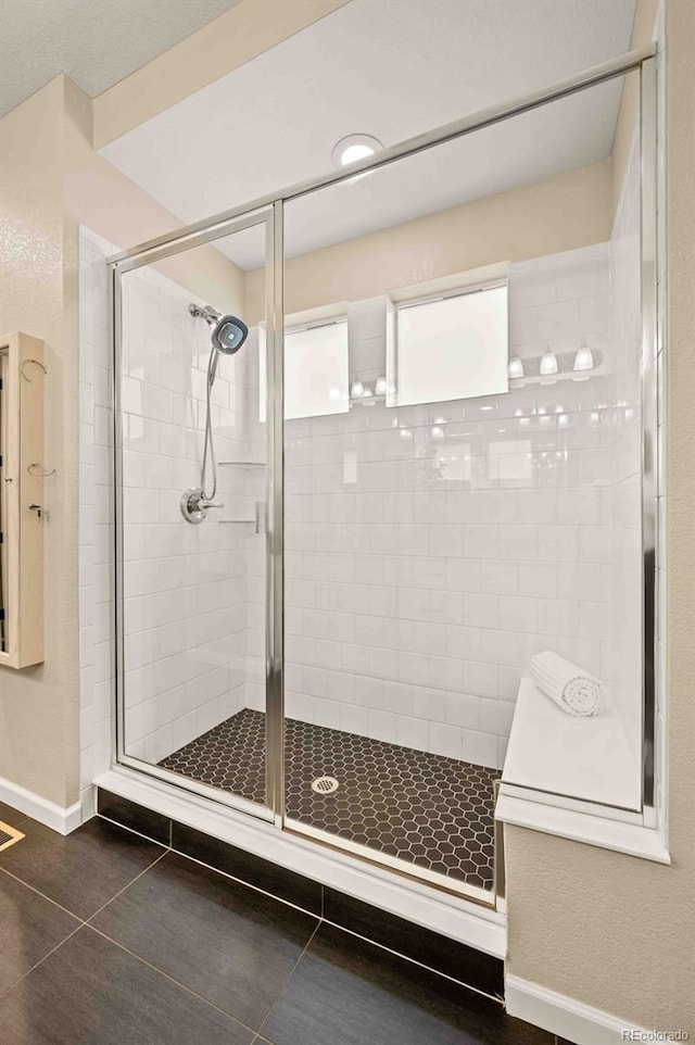 bathroom with tile patterned flooring, a shower stall, and baseboards