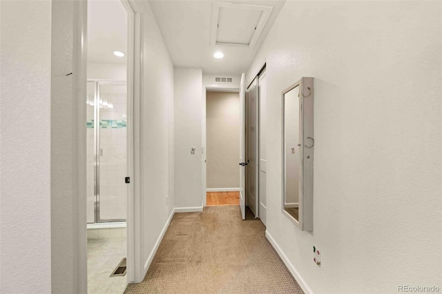 corridor featuring visible vents, light carpet, and baseboards