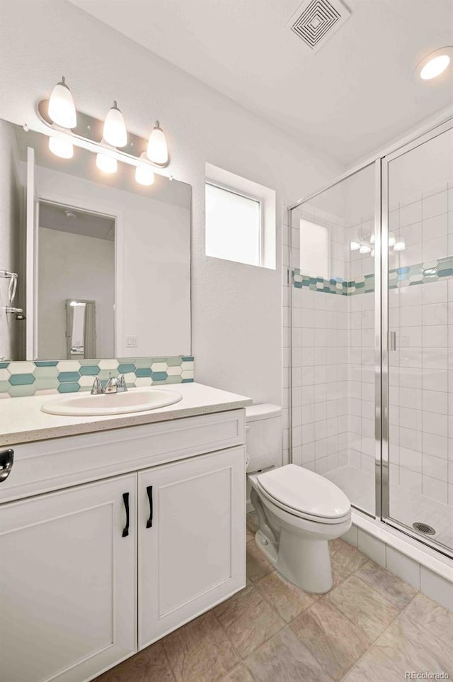 bathroom featuring toilet, a stall shower, visible vents, and vanity