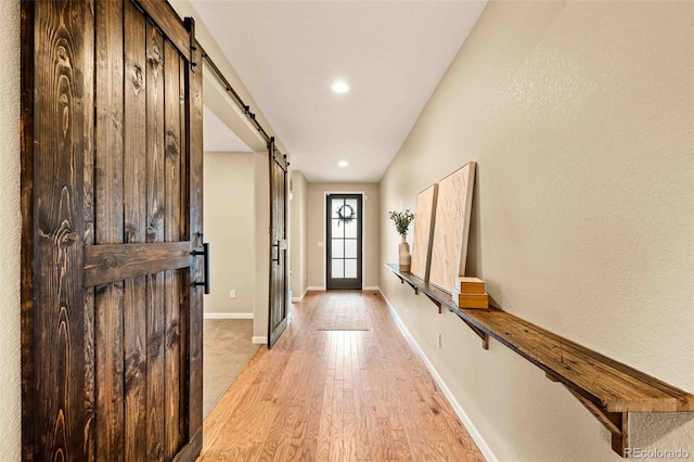 doorway featuring light wood finished floors, a barn door, and baseboards