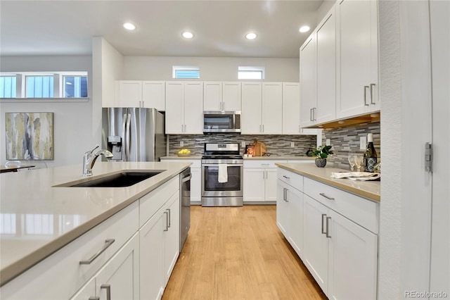 kitchen featuring a wealth of natural light, stainless steel appliances, sink, and white cabinetry