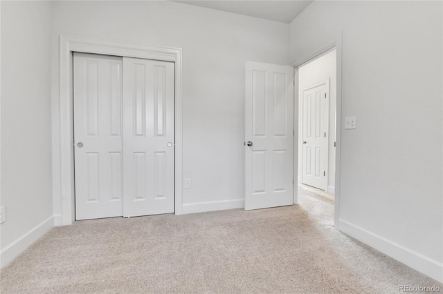 unfurnished bedroom with a closet and light colored carpet