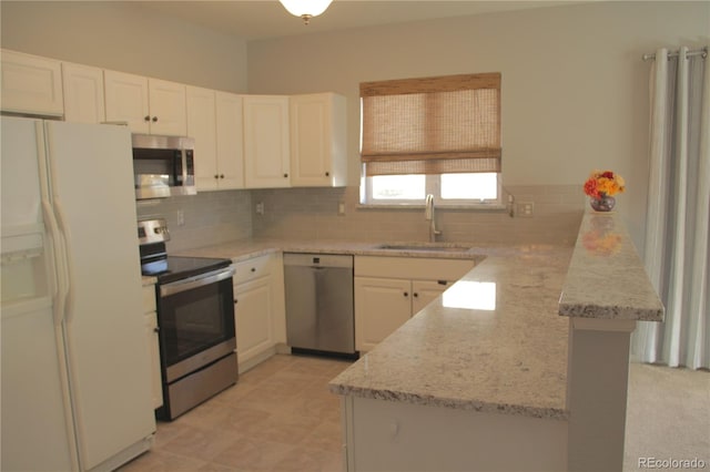 kitchen featuring white cabinetry, sink, light stone counters, kitchen peninsula, and appliances with stainless steel finishes