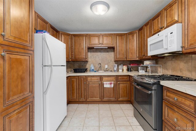 544 S 3rd Ave, Brighton, CO 80601 - kitchen featuring white appliances, brown cabinetry, a sink, tasteful backsplash, and a textured ceiling