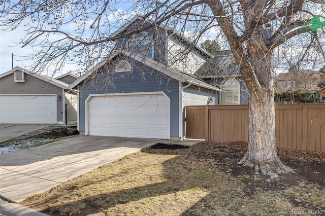 garage featuring driveway and fence