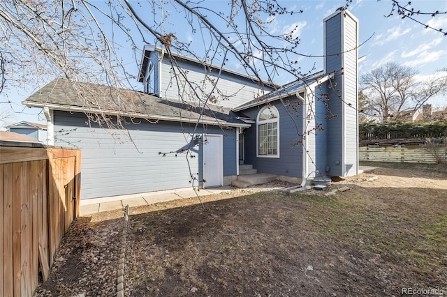 rear view of house featuring fence and a chimney