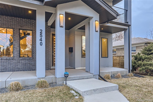 entrance to property featuring brick siding and covered porch