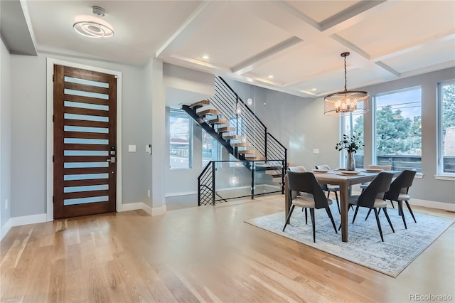 dining space with a healthy amount of sunlight, light hardwood / wood-style flooring, coffered ceiling, and a notable chandelier