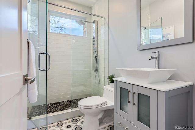 bathroom with a stall shower, toilet, and vanity