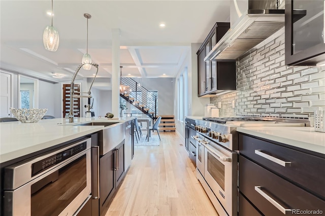 kitchen with decorative backsplash, appliances with stainless steel finishes, light countertops, and wall chimney range hood