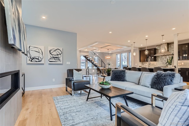 living room featuring recessed lighting, light wood-style flooring, stairs, and baseboards