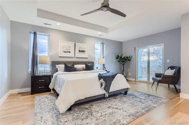 bedroom featuring visible vents, a raised ceiling, baseboards, and access to outside