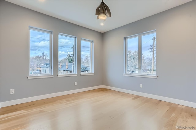 unfurnished room with light wood-type flooring and baseboards