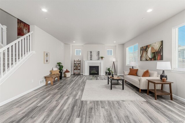 12941 Delaware St, Westminster, CO 80234 - living area featuring wood finished floors, stairs, recessed lighting, baseboards, and a glass covered fireplace
