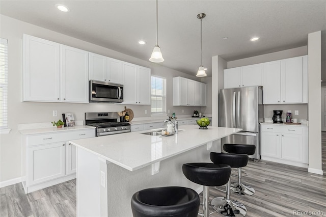 12941 Delaware St, Westminster, CO 80234 - kitchen featuring appliances with stainless steel finishes, a sink, a breakfast bar area, light wood finished floors, and light countertops