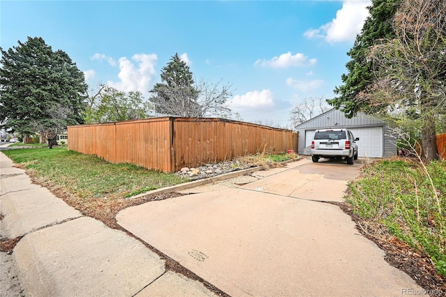 view of side of home with an outbuilding, a detached garage, fence, and concrete driveway