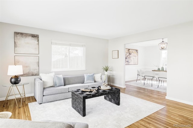 living room featuring baseboards, wood finished floors, and an inviting chandelier