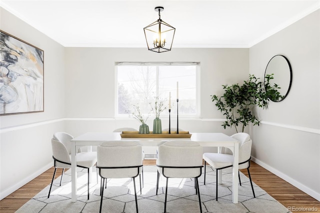 dining area with crown molding, baseboards, wood finished floors, and a notable chandelier