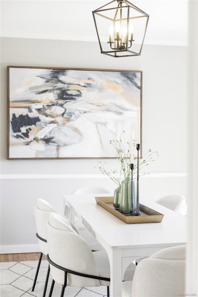 dining room featuring baseboards, a notable chandelier, ornamental molding, and wood finished floors