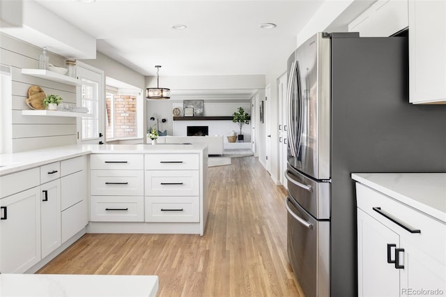 kitchen with white cabinets, open shelves, light countertops, freestanding refrigerator, and light wood-type flooring