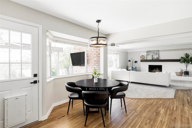 dining room with an inviting chandelier, visible vents, wood finished floors, a fireplace, and baseboards