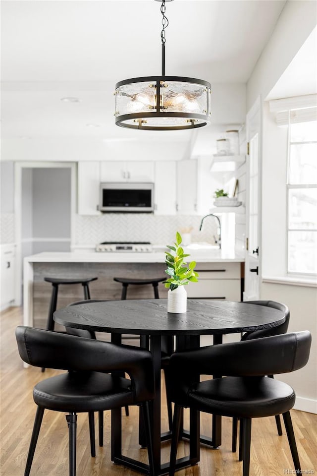 dining space featuring baseboards, light wood-style flooring, and a chandelier