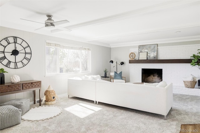 living room with ceiling fan, carpet, a brick fireplace, and beam ceiling