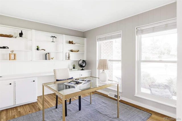 office with light wood-style floors, baseboards, and crown molding