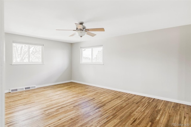 empty room featuring visible vents, baseboards, ceiling fan, and wood finished floors