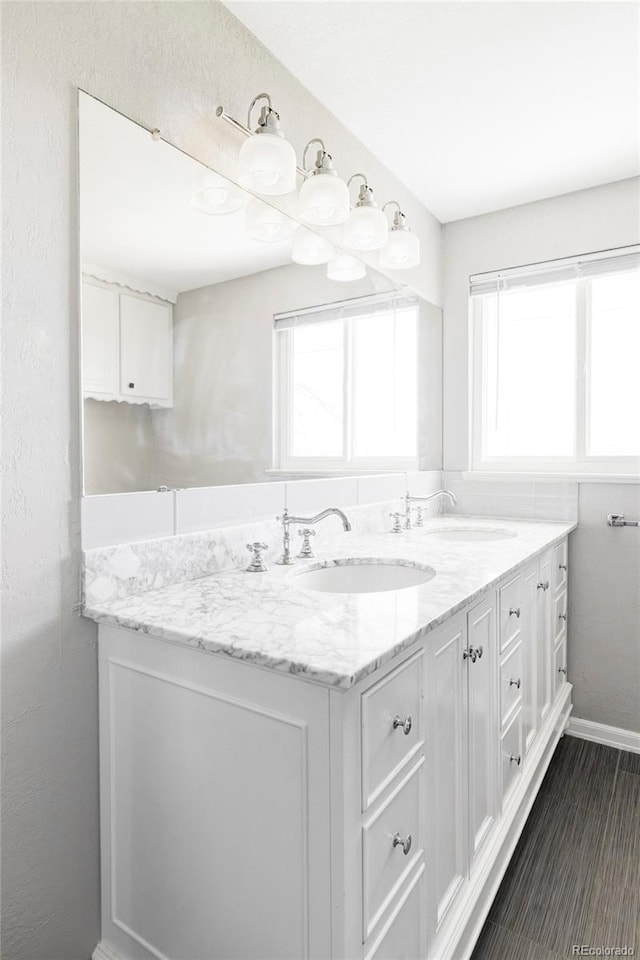 bathroom with double vanity, baseboards, and a sink