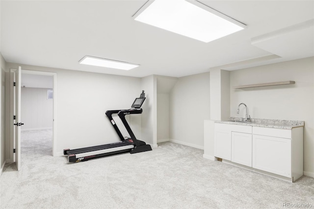 workout area featuring a sink, baseboards, wet bar, and light colored carpet