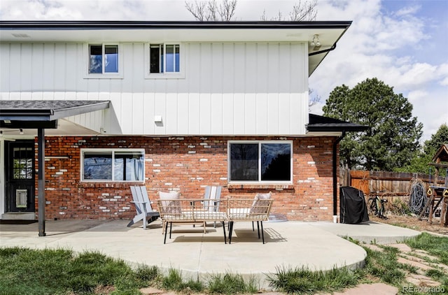 rear view of property with brick siding, fence, and a patio